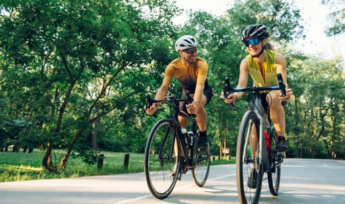 Two people riding bikes outdoors.