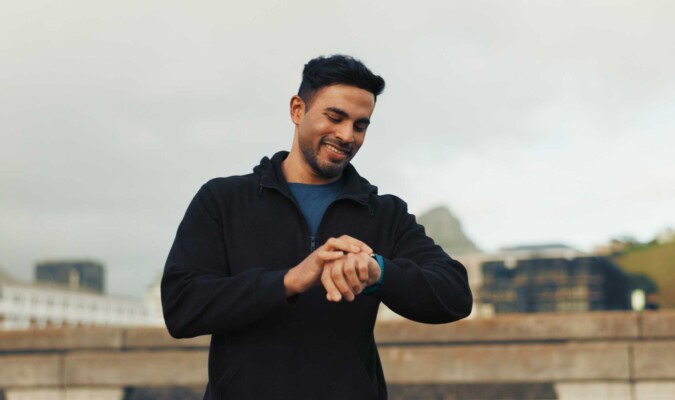 A man outdoors checking his watch.