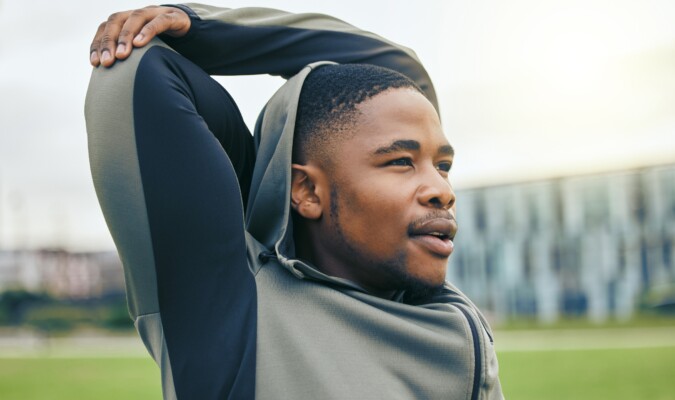 Man in jacket stretching outside.